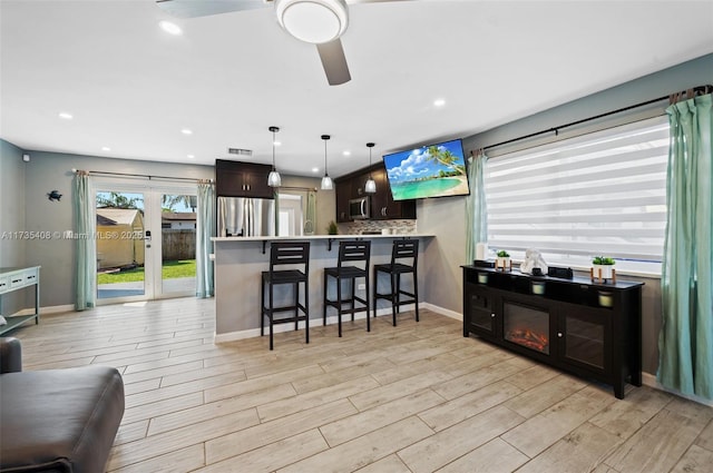 kitchen with tasteful backsplash, light wood-type flooring, a kitchen breakfast bar, kitchen peninsula, and stainless steel appliances