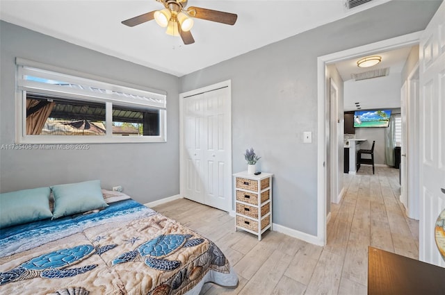 bedroom with multiple windows, ceiling fan, light wood-type flooring, and a closet