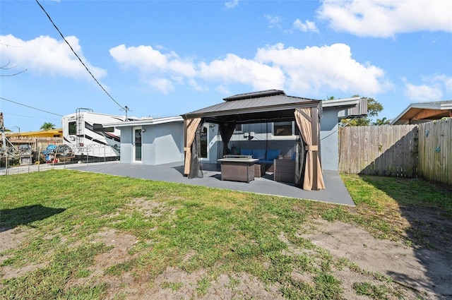 back of property featuring a yard, a gazebo, a patio area, and an outdoor living space with a fire pit