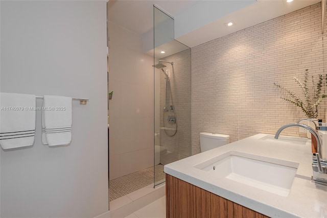 bathroom featuring a tile shower, vanity, and toilet