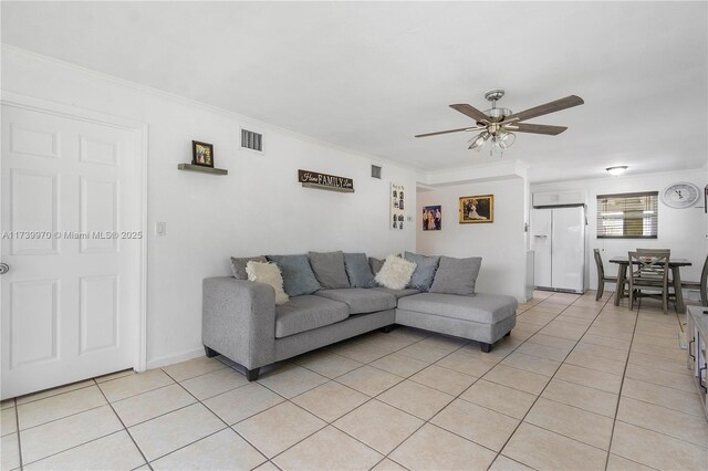 tiled living room with crown molding and ceiling fan