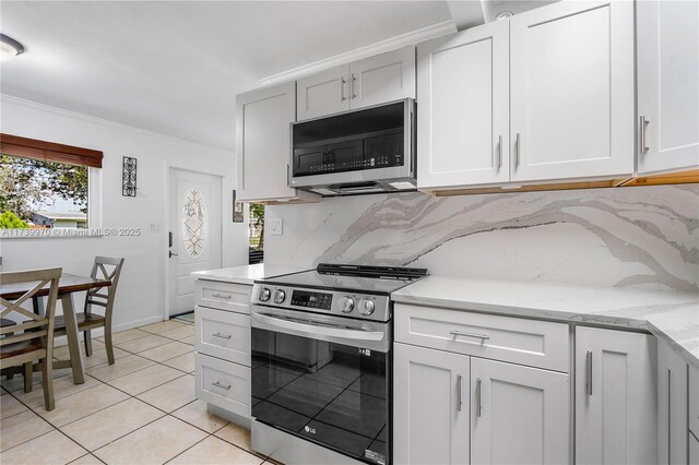 kitchen with white cabinetry, ornamental molding, stainless steel appliances, and light tile patterned flooring