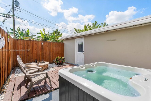 view of patio featuring a hot tub, a wooden deck, and an outdoor fire pit