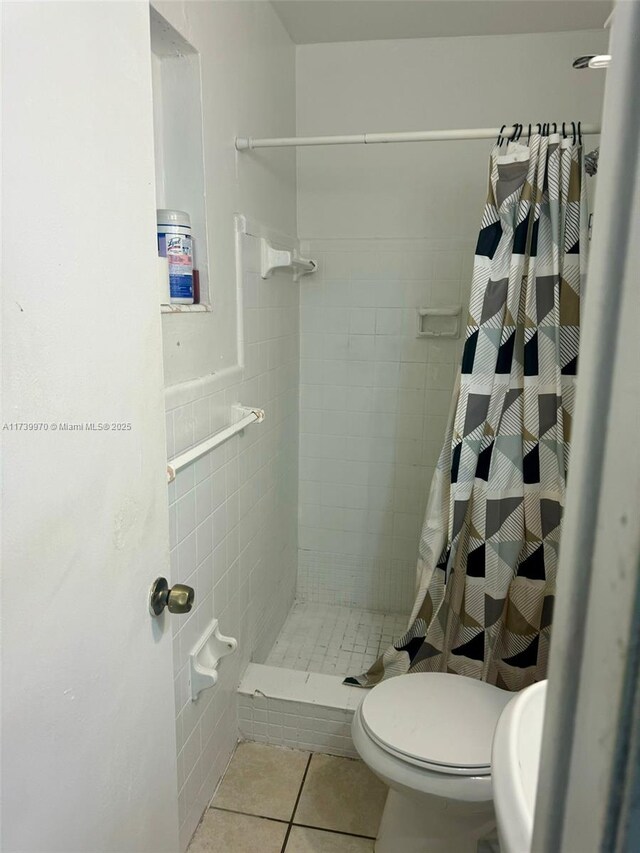 bathroom featuring curtained shower, tile patterned floors, and toilet