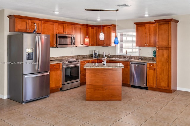 kitchen featuring sink, appliances with stainless steel finishes, hanging light fixtures, a center island, and light stone countertops