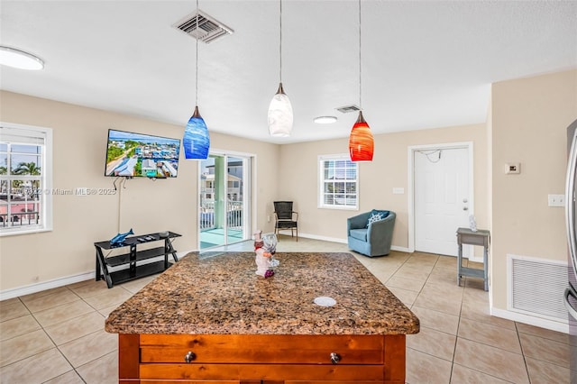 kitchen featuring hanging light fixtures, light tile patterned floors, and dark stone counters