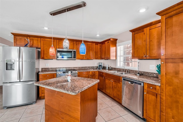 kitchen featuring appliances with stainless steel finishes, sink, hanging light fixtures, a center island, and light stone countertops