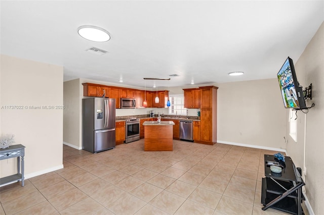 kitchen with pendant lighting, appliances with stainless steel finishes, a center island, and light tile patterned floors