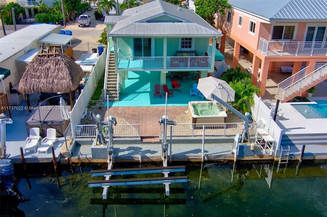 back of house featuring a water view, a patio, and a swimming pool