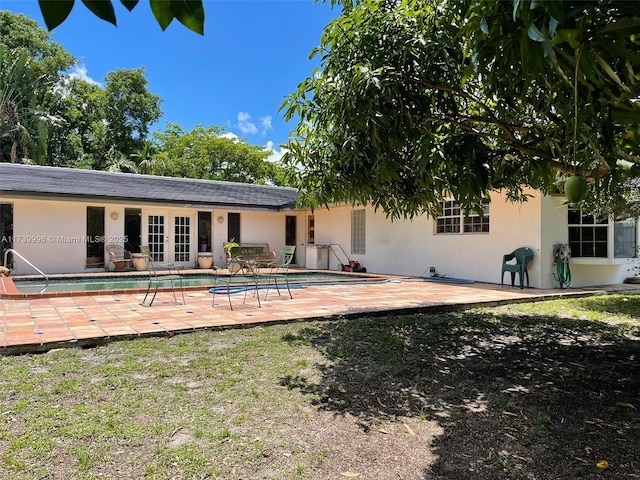 rear view of house with french doors, roof with shingles, a patio, stucco siding, and an outdoor pool