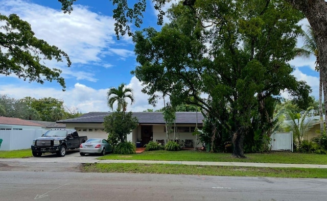 ranch-style house with an attached garage, driveway, fence, and a front yard