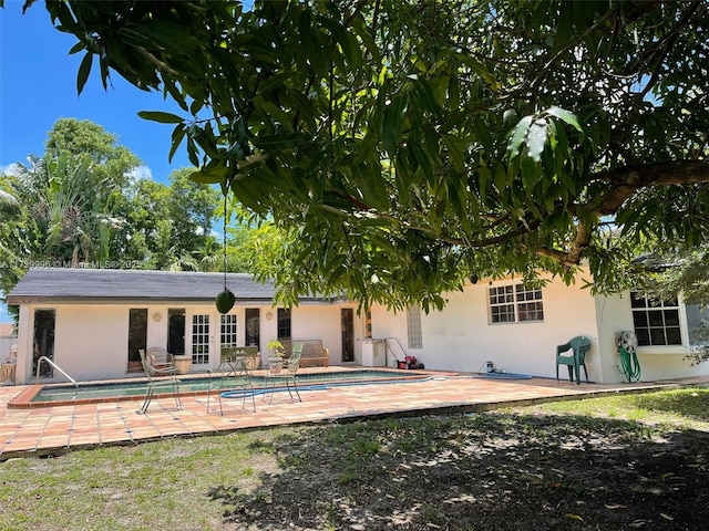 rear view of property featuring a patio, an outdoor pool, and stucco siding