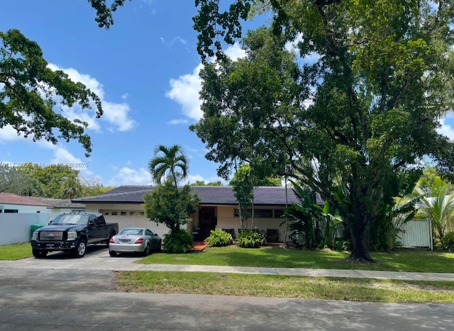 ranch-style home with a garage, a front yard, driveway, and fence