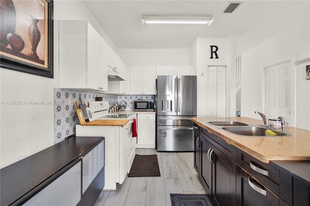 kitchen featuring sink, stainless steel fridge, wooden counters, and white cabinets