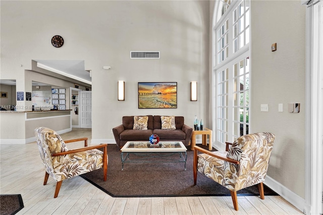 living room with light hardwood / wood-style flooring and a high ceiling