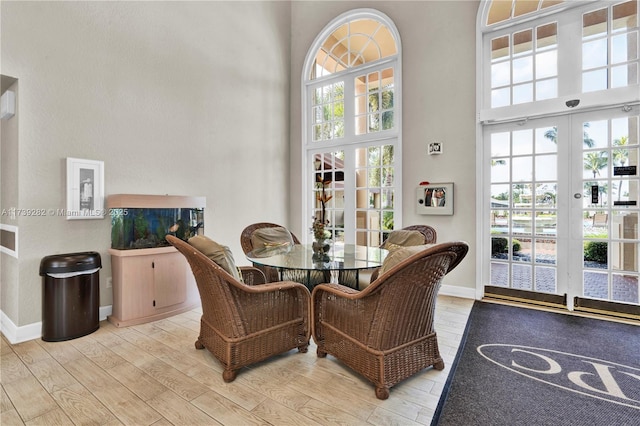 dining room featuring light hardwood / wood-style floors, french doors, and a high ceiling