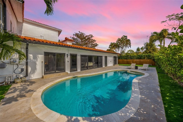 pool at dusk with a fenced in pool, fence private yard, and a patio area