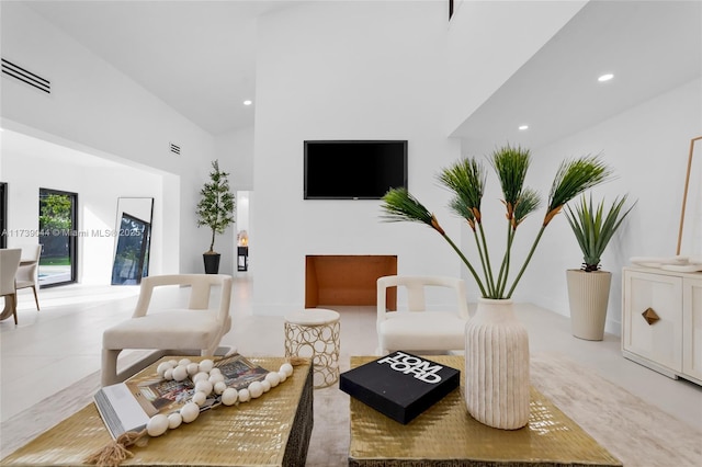 living area with recessed lighting, visible vents, and a towering ceiling