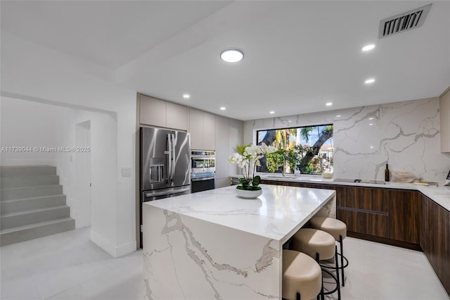 kitchen with stainless steel appliances, visible vents, light stone counters, and modern cabinets