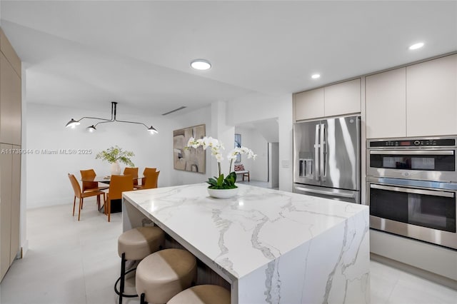 kitchen with light stone counters, recessed lighting, stainless steel appliances, a center island, and modern cabinets