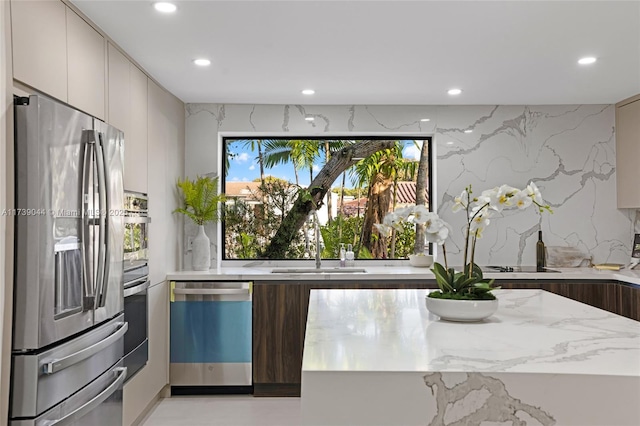 kitchen with modern cabinets, light stone countertops, stainless steel appliances, a sink, and recessed lighting