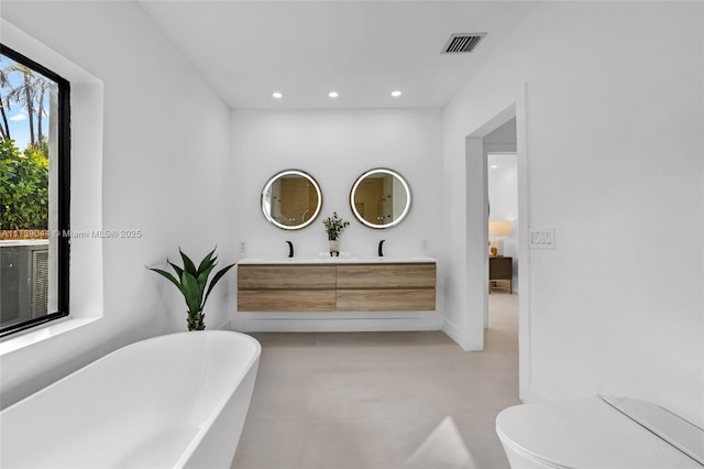 ensuite bathroom featuring double vanity, visible vents, ensuite bathroom, a freestanding tub, and recessed lighting