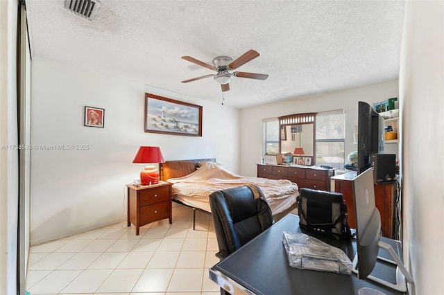 tiled bedroom featuring ceiling fan and a textured ceiling