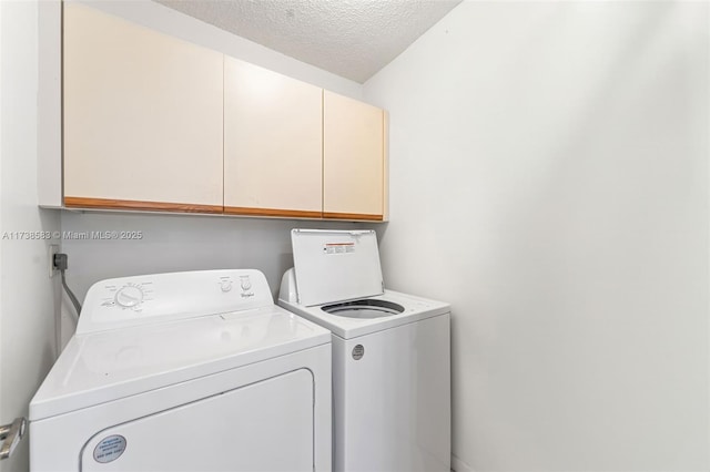 washroom featuring cabinets, a textured ceiling, and washing machine and clothes dryer