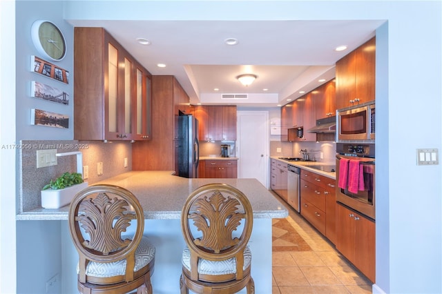 kitchen featuring a peninsula, visible vents, light countertops, decorative backsplash, and black appliances