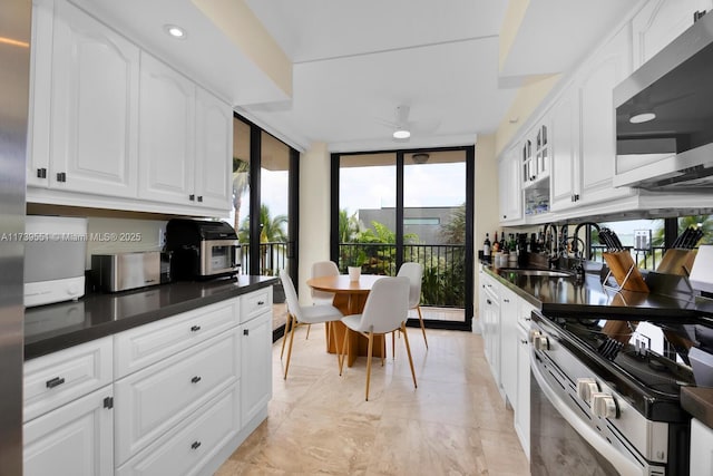 kitchen with white cabinets, a ceiling fan, dark countertops, stainless steel appliances, and a sink