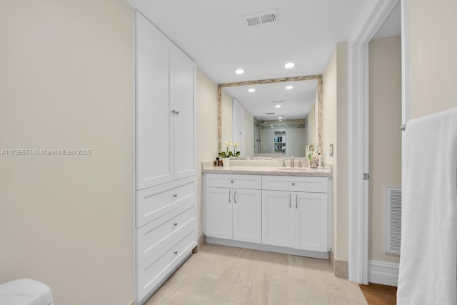 bathroom with visible vents, vanity, toilet, and wood finished floors