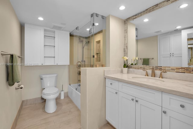 full bathroom featuring toilet, shower / bath combination with glass door, recessed lighting, and vanity