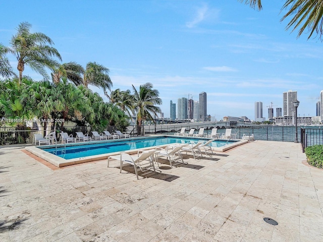 community pool with a city view, a patio, and fence