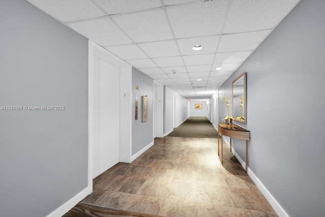 hallway with a paneled ceiling, baseboards, and recessed lighting