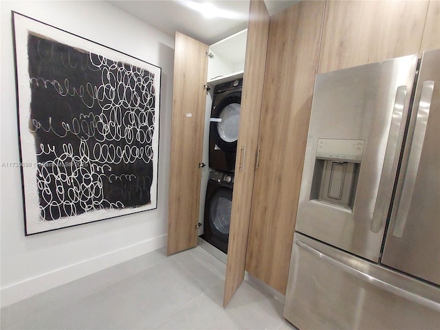 interior space featuring stacked washing maching and dryer and stainless steel fridge