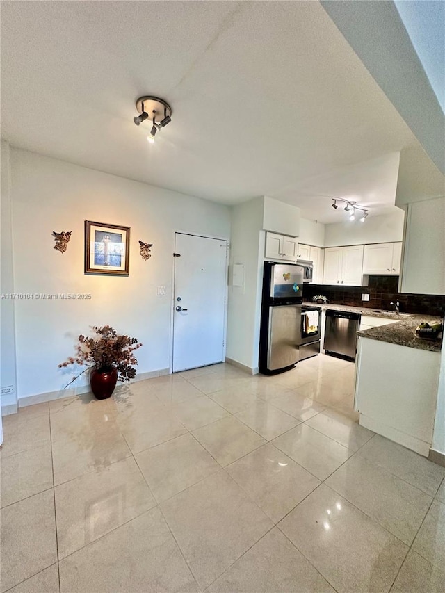 kitchen with light tile patterned flooring, appliances with stainless steel finishes, white cabinetry, backsplash, and a textured ceiling