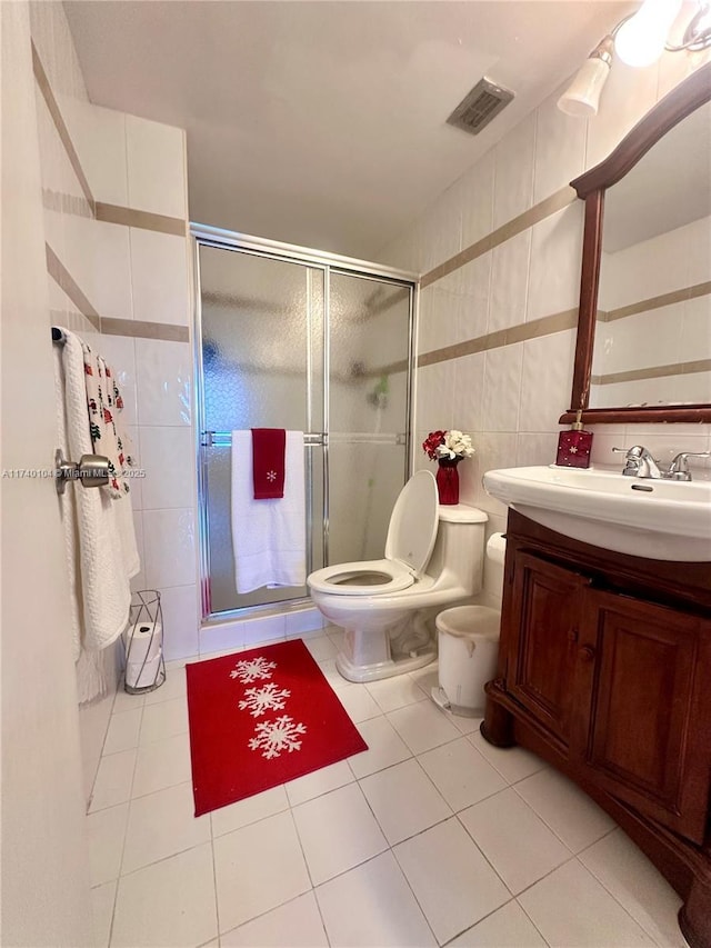 bathroom with walk in shower, tile patterned floors, toilet, tile walls, and vanity