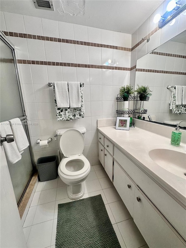 bathroom featuring tile walls, vanity, a shower with shower door, tile patterned floors, and toilet