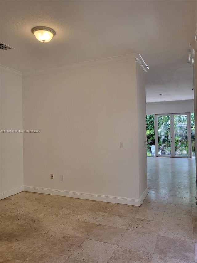 spare room featuring visible vents, baseboards, and crown molding