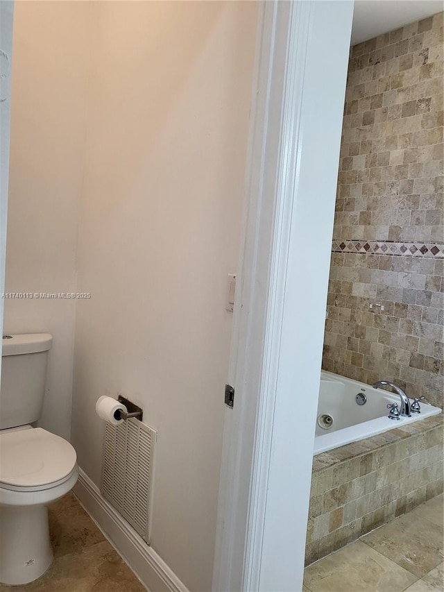 bathroom with tile patterned floors, tiled bath, and toilet