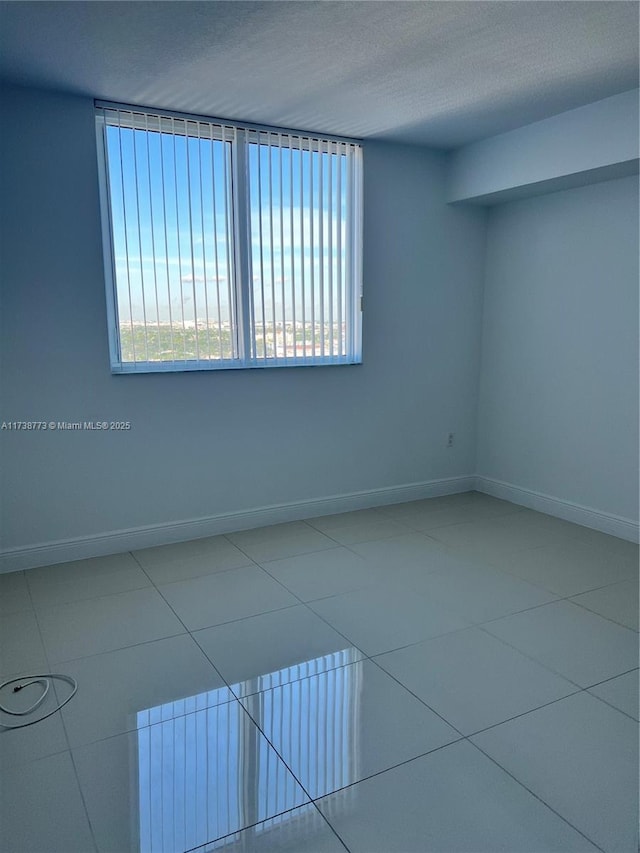 tiled empty room featuring a textured ceiling