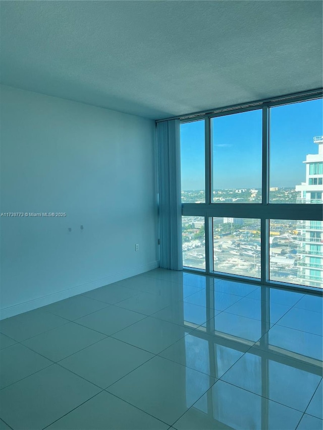 spare room featuring tile patterned floors, floor to ceiling windows, and a textured ceiling