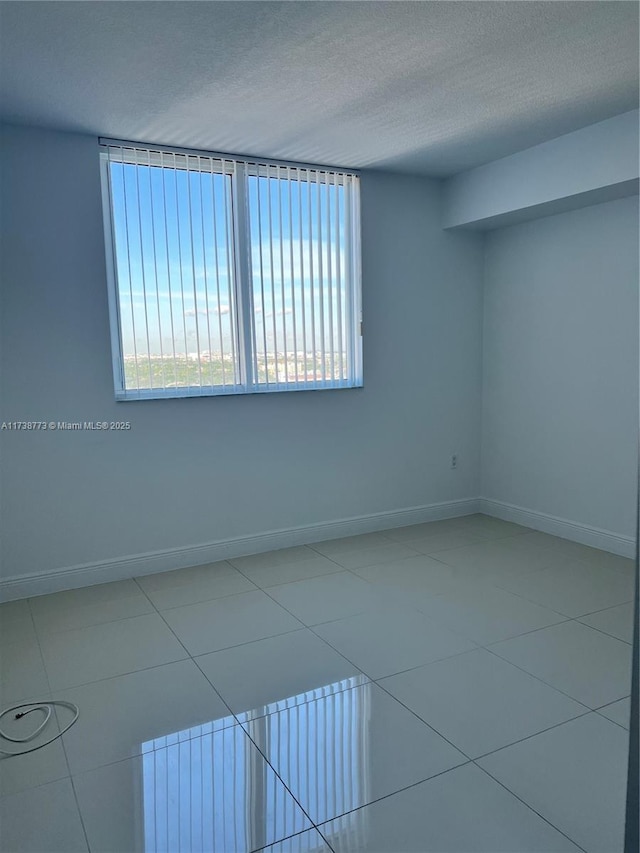 tiled empty room with a textured ceiling