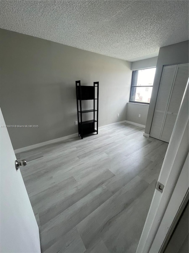 empty room with light hardwood / wood-style flooring and a textured ceiling