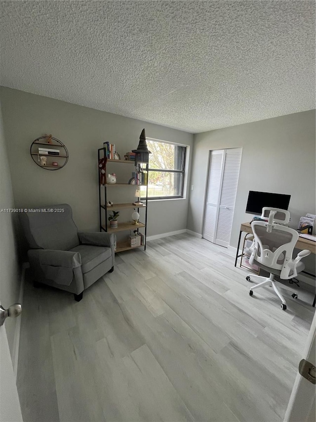 home office with a textured ceiling and light wood-type flooring