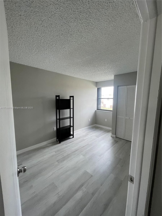 empty room with light hardwood / wood-style flooring and a textured ceiling