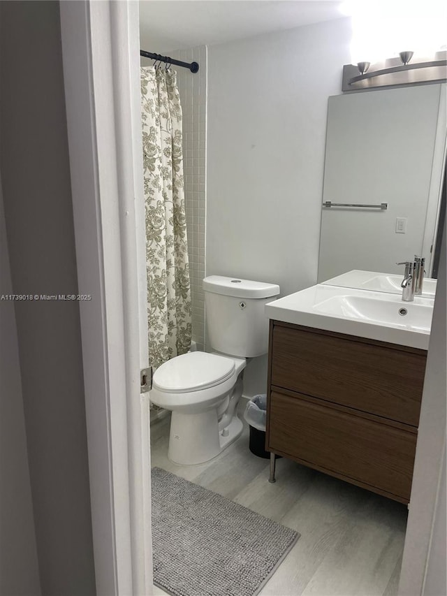 bathroom with hardwood / wood-style flooring, vanity, walk in shower, and toilet