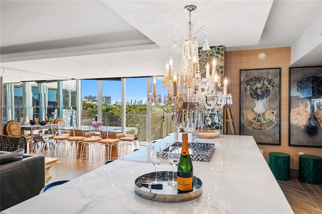 dining area featuring a raised ceiling, floor to ceiling windows, and a notable chandelier