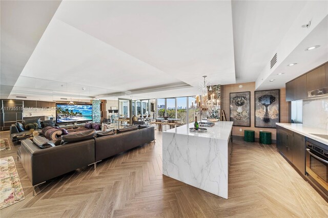 living room featuring light parquet flooring, a chandelier, and a raised ceiling