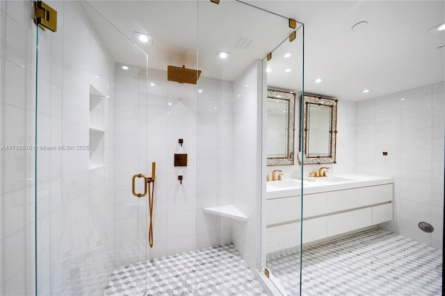 bathroom with an enclosed shower, sink, and tile walls